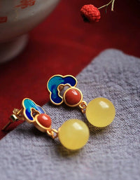 Colorful earrings with yellow and red stones on a textured surface