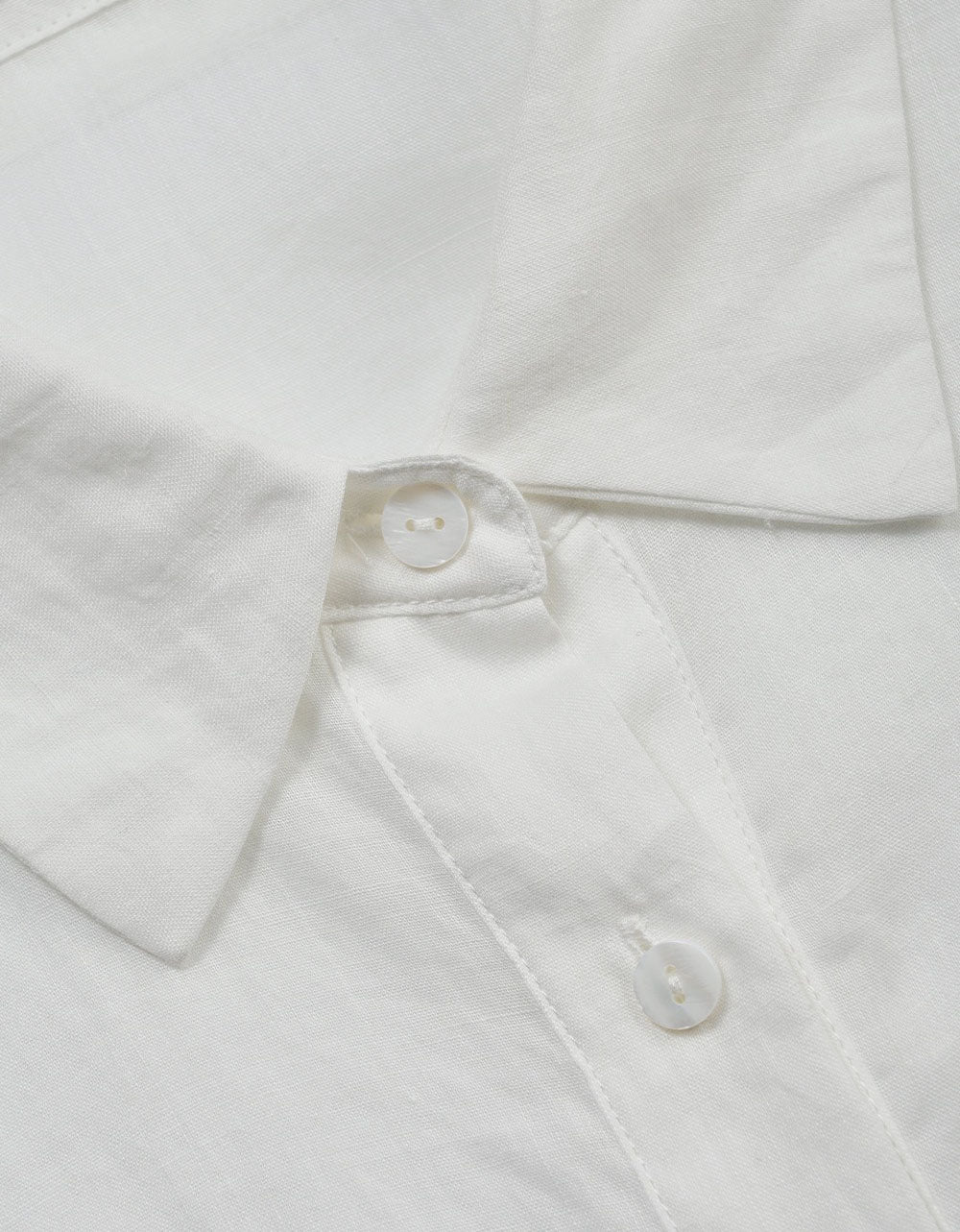 Close-up of a white shirt with buttons on a light gray background