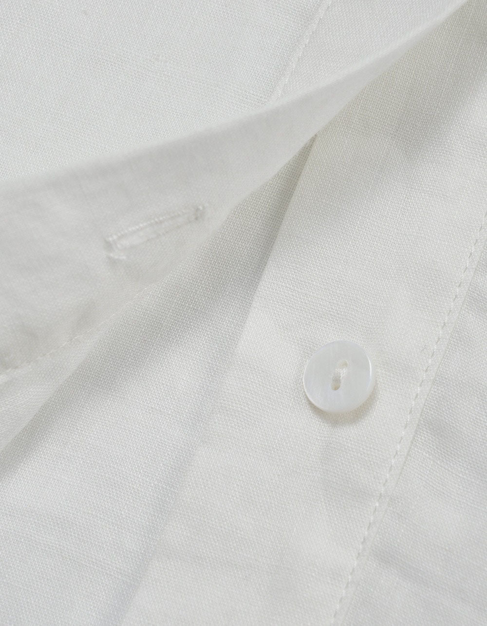 Close-up of a white shirt with a button on a light gray background
