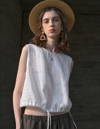 Woman wearing a white sleeveless top and brown hat against a dark background