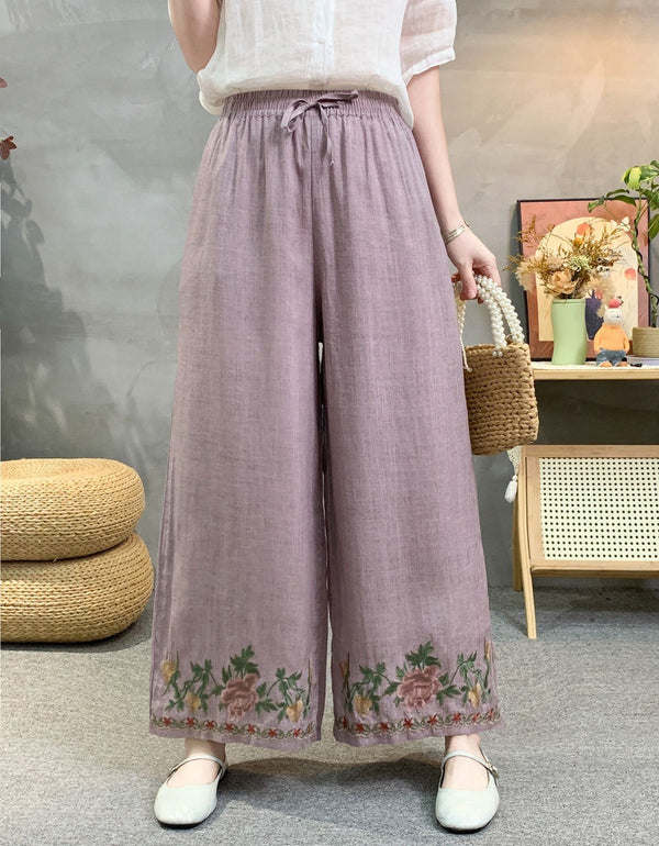 Purple linen wide leg pants with floral embroidered hem and elastic waist, styled with white top.