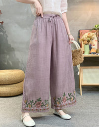 Purple linen wide leg pants with floral embroidered hem and elastic waist, styled with white top side view