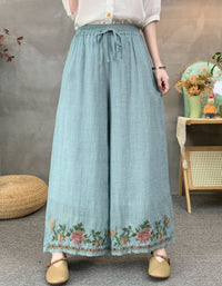 Vintage style blue linen pants featuring wide legs and detailed floral hem embroidery.