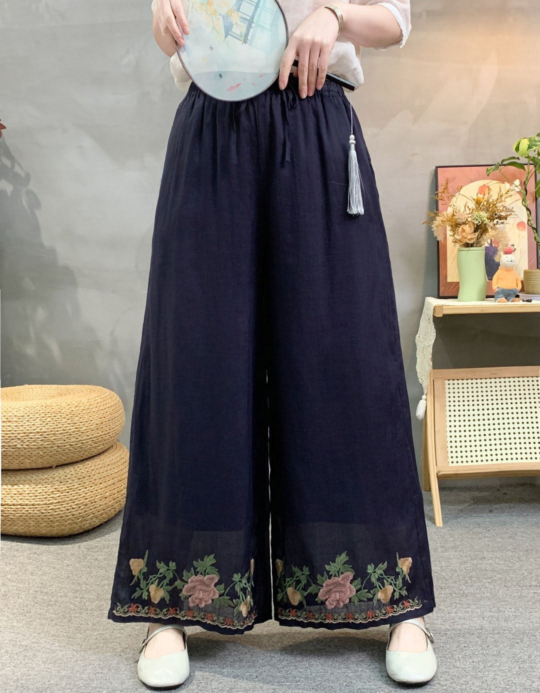Navy linen wide leg pants with floral embroidered hem and elastic waist, styled with white top.