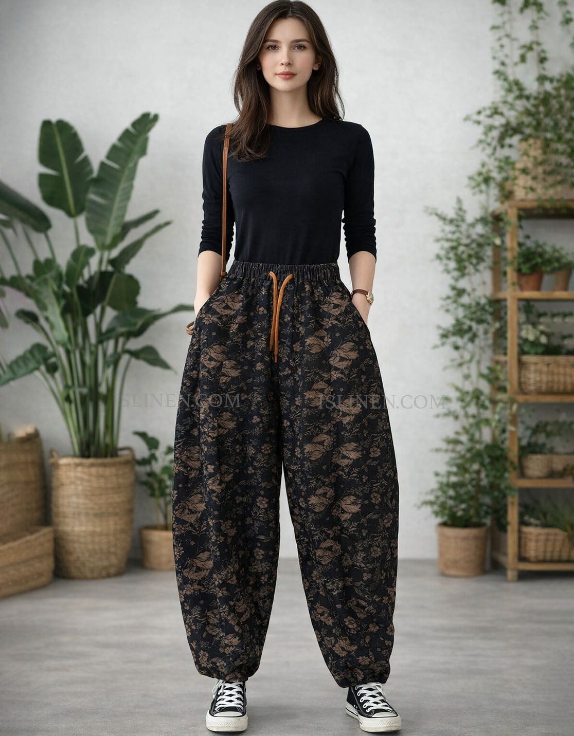 Woman wearing a black top and floral pants in a room with plants