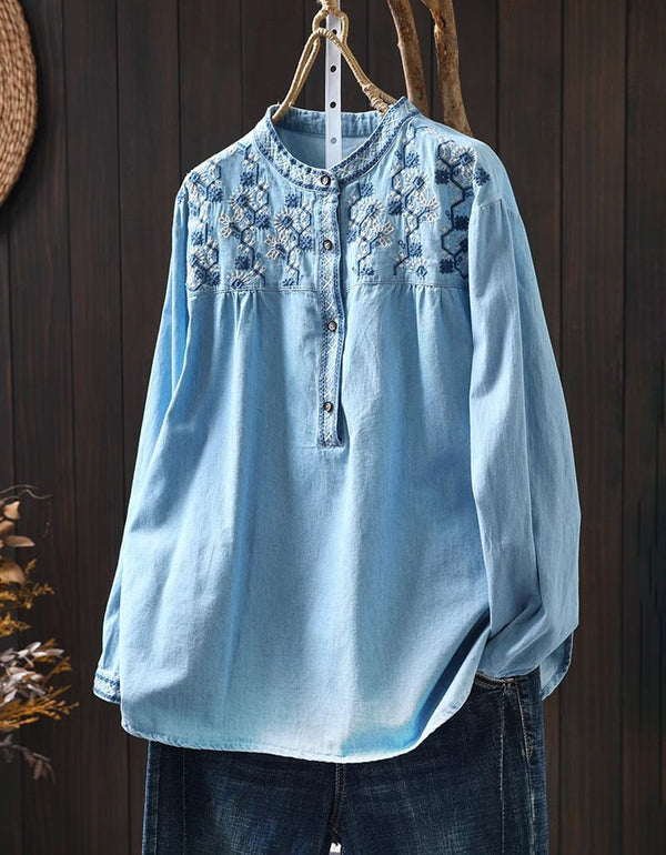 Front view of women's light blue embroidered denim shirt with floral design and button-down closure.