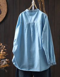 Back view of women's light blue embroidered denim shirt with floral design and button-down closure.