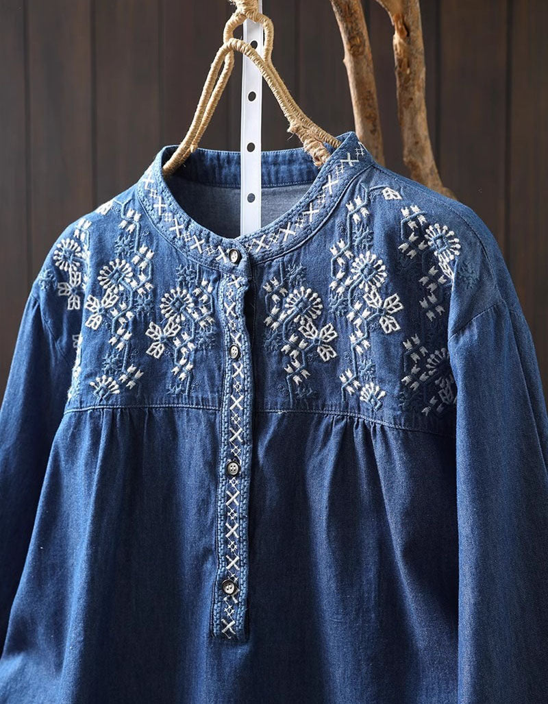 Close-up of the delicate floral embroidery on the blue women's denim shirt, showcasing the button-down detail.