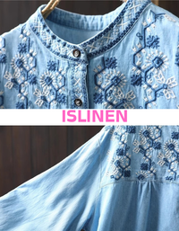 Close-up of women's embroidered denim shirt showing fine stitching and button-down design.