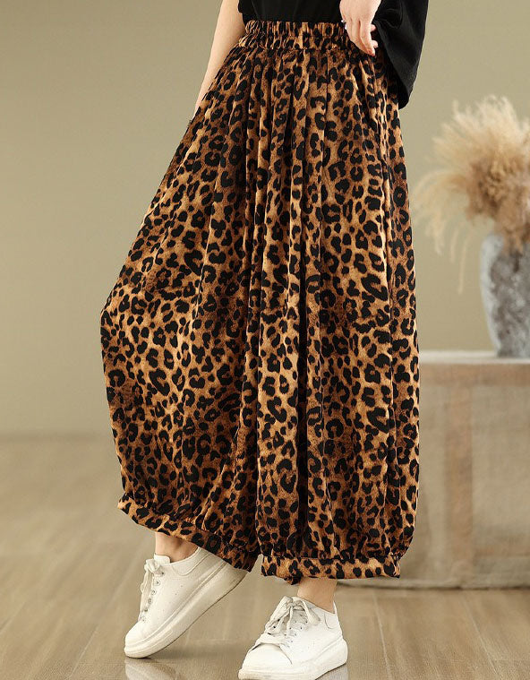 Side view of a woman wearing leopard print wide-leg pants with a black top and sneakers.