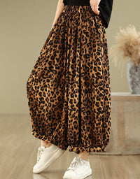 Side view of a woman wearing leopard print wide-leg pants with a black top and sneakers.