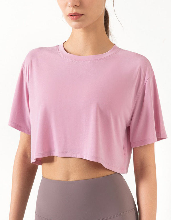 Person wearing a pink crop top and gray leggings on a white background