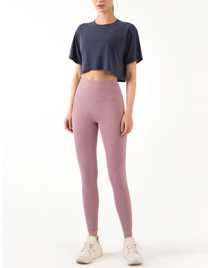 Person wearing a navy crop top and pink leggings on a white background full view