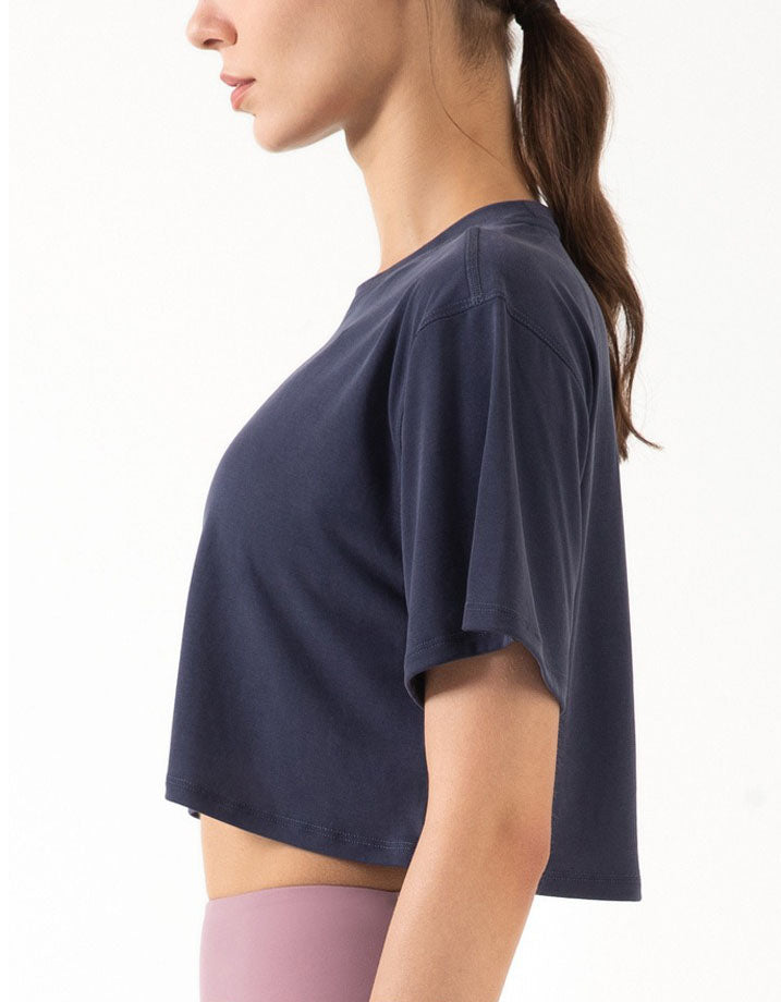 Person wearing a navy blue crop top on a white background side view
