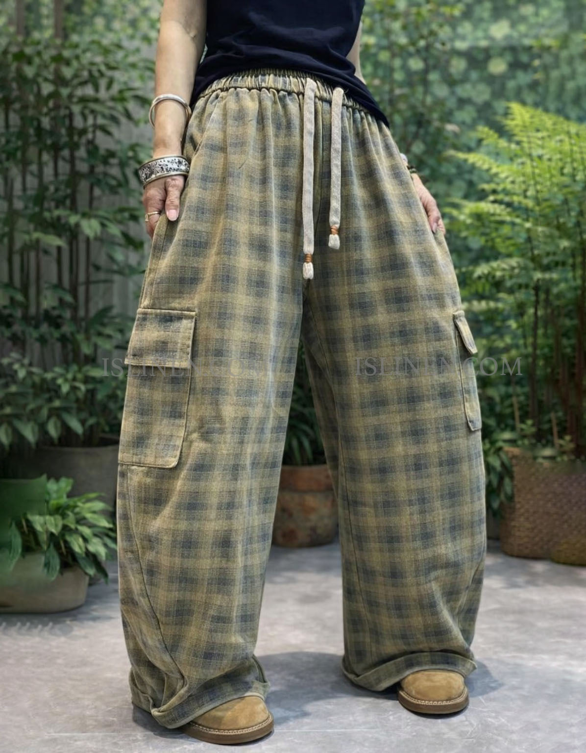 Woman wearing oversized green plaid wide leg cargo pants styled with black top and casual shoes outdoors.