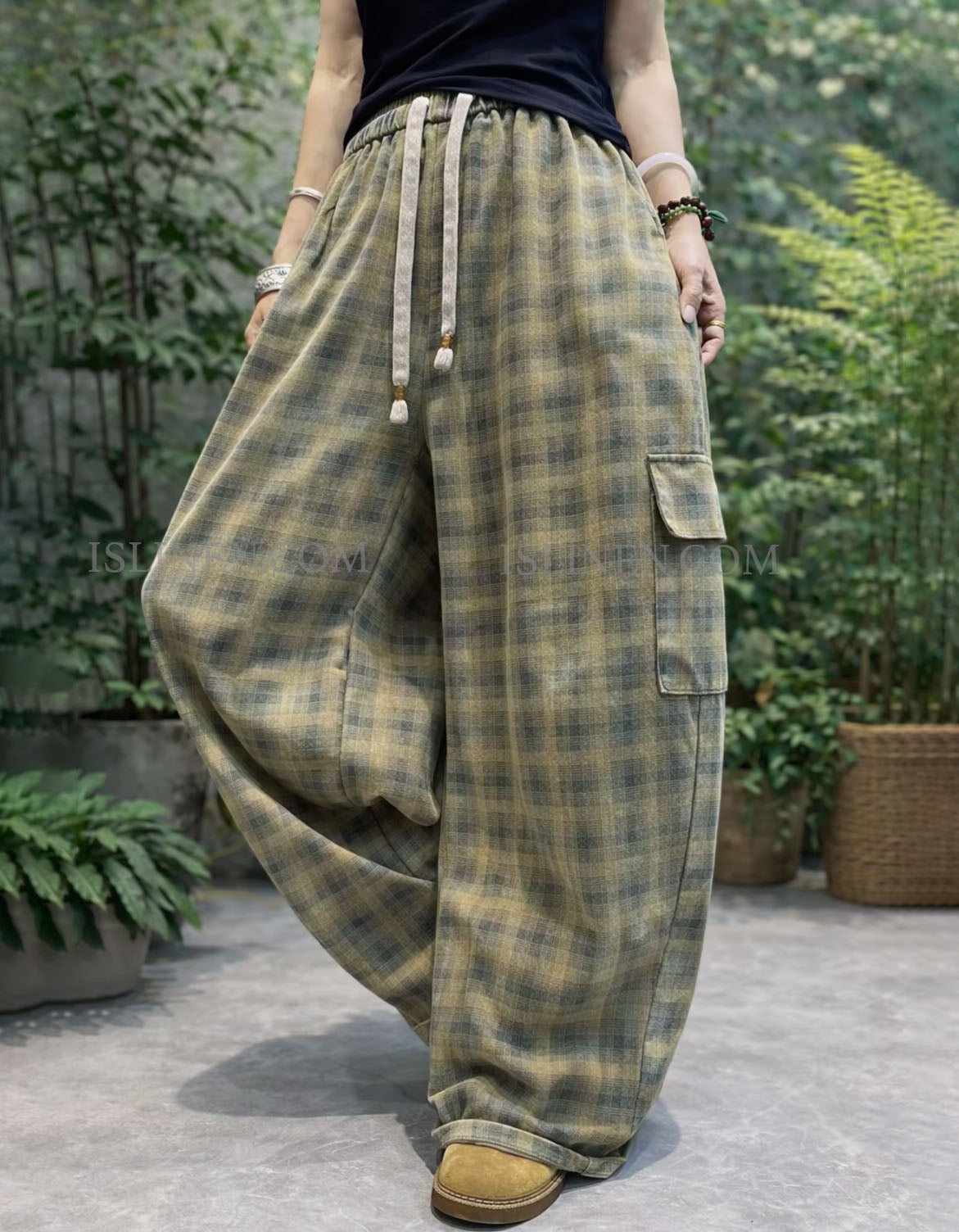 Person wearing plaid wide-leg pants with a garden background