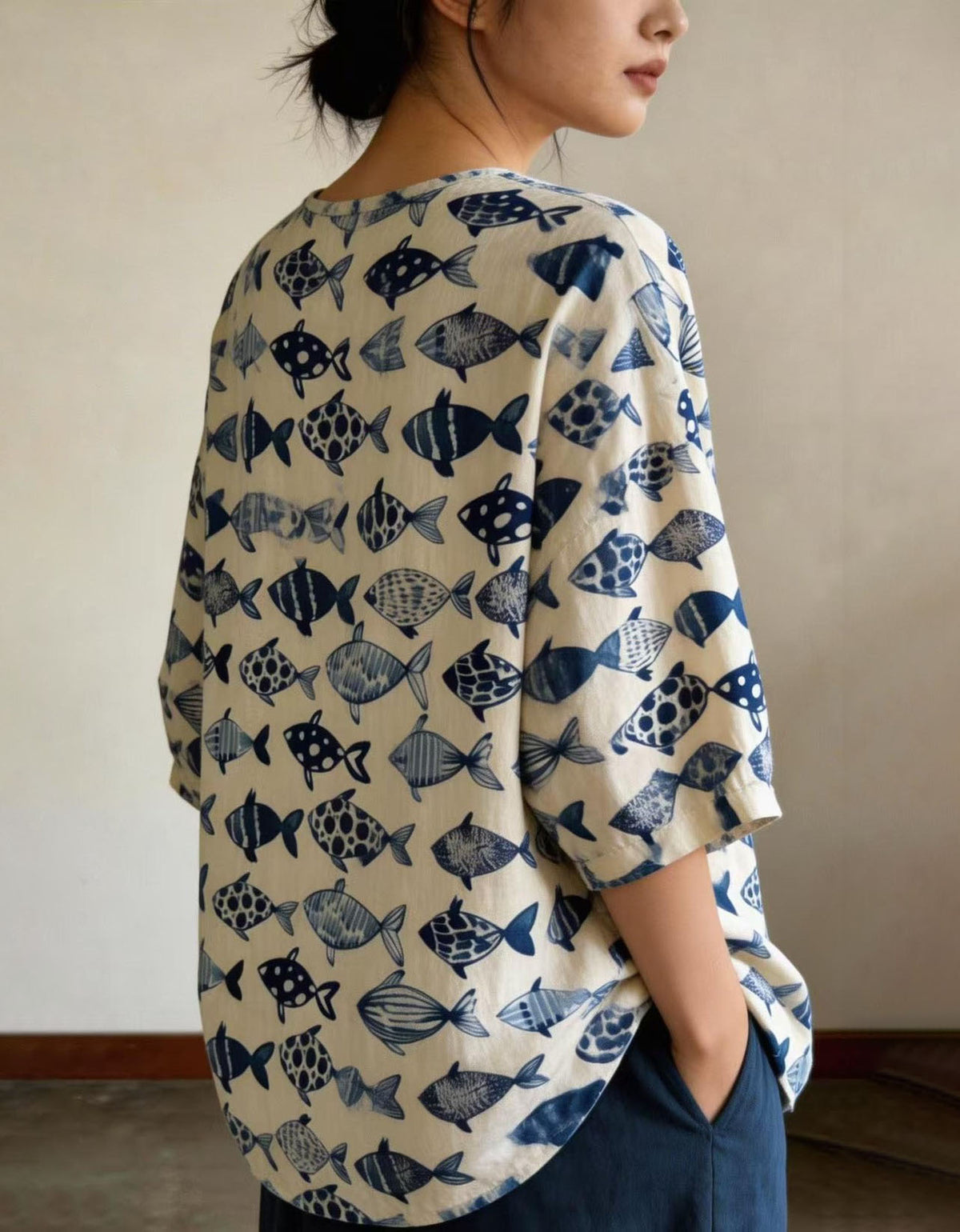 Side view of women wearing relaxed blue fish linen top styled with wide leg pants