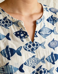 Close up of blue fish print on natural linen fabric women’s summer shirt