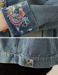 Close-up of a denim jacket with embroidered cuffs and button details.
