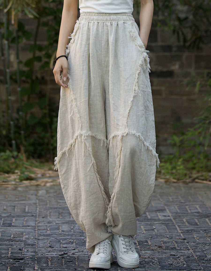 Person wearing beige distressed wide-leg pants and white sneakers on a brick path.