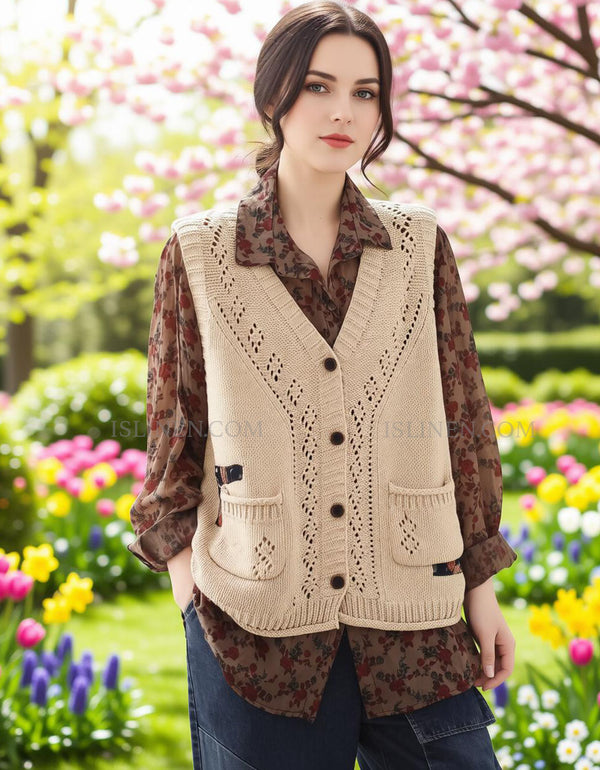 Woman wearing a beige knitted vest in a garden with flowers and trees.