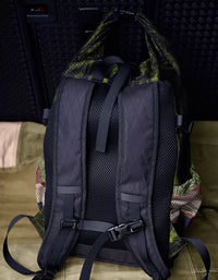 Close‑up of green topographic print front zip pocket and magenta zipper on roll top backpack.