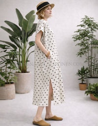 Side view of relaxed cream polka dot midi dress showing side slit and straight silhouette.