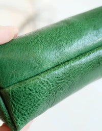 Close-up of a green leather-bound book held by a hand on a white background