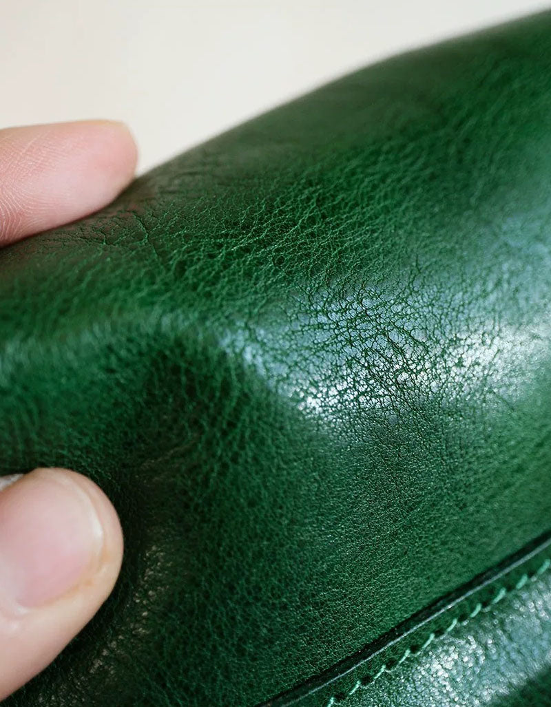 Close-up of a hand holding green leather, focusing on texture and color.