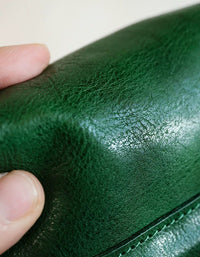 Close-up of a hand holding green leather, focusing on texture and color.