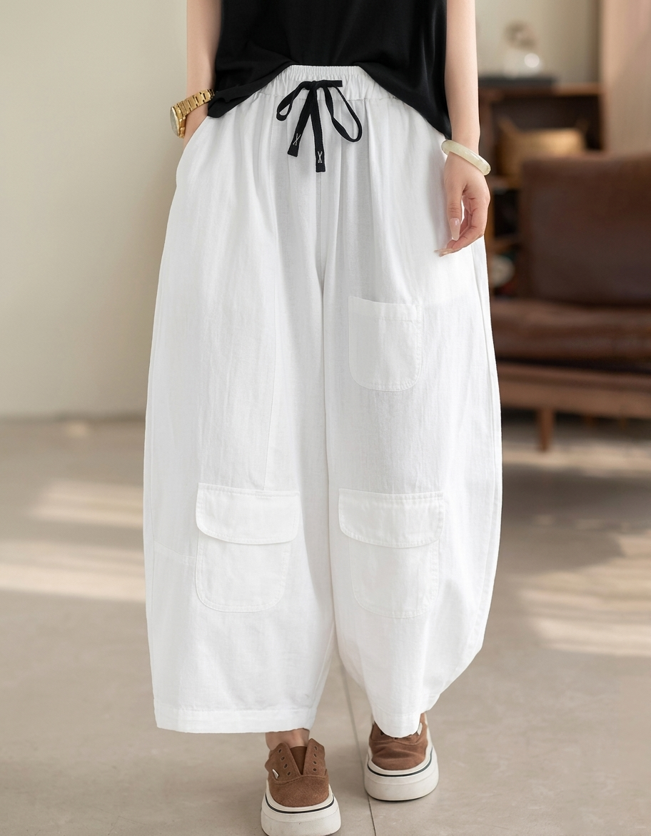 Front view of woman wearing white wide leg cargo pants with black drawstring.