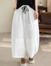 Front view of woman wearing white wide leg cargo pants with black drawstring.