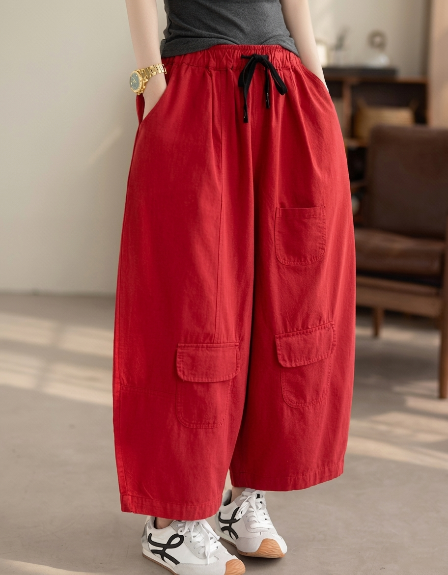 Model wearing red balloon pants with white sneakers in a minimalist room.
