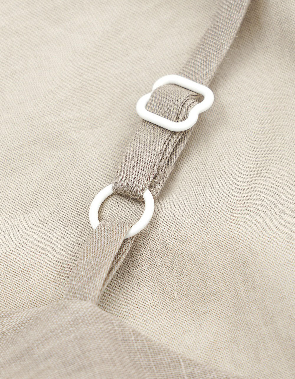 Close-up of beige fabric with a strap and white buckle.