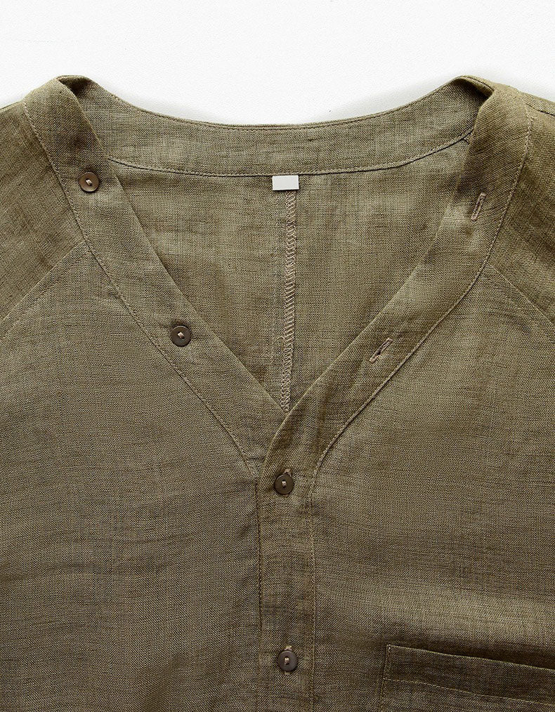 Close-up of relaxed olive linen V‑neck shirt with long sleeves and slightly cropped elastic hem.