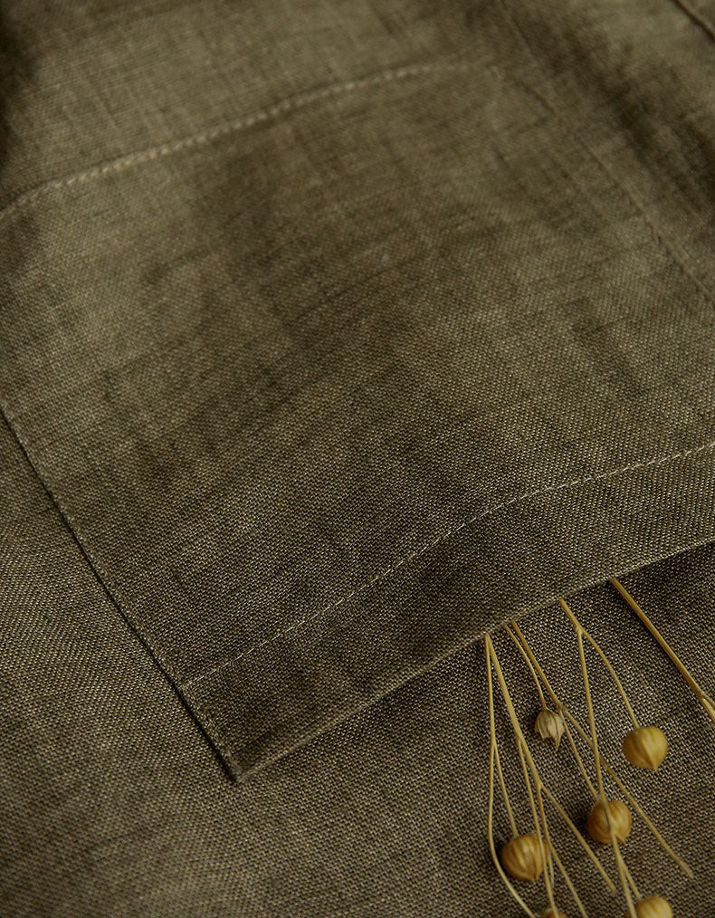Close-up of a olive green fabric with a textured pattern and a dried plant stem.