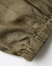 Close-up of olive green fabric with an elastic waistband on a white background