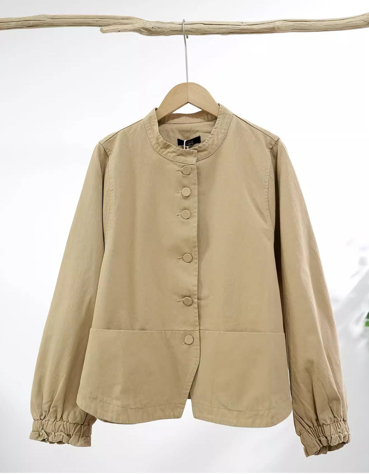Beige jacket on a hanger against a white background