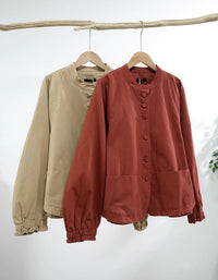 Two jackets, one beige and one rust-colored, hanging on wooden hangers against a white background.