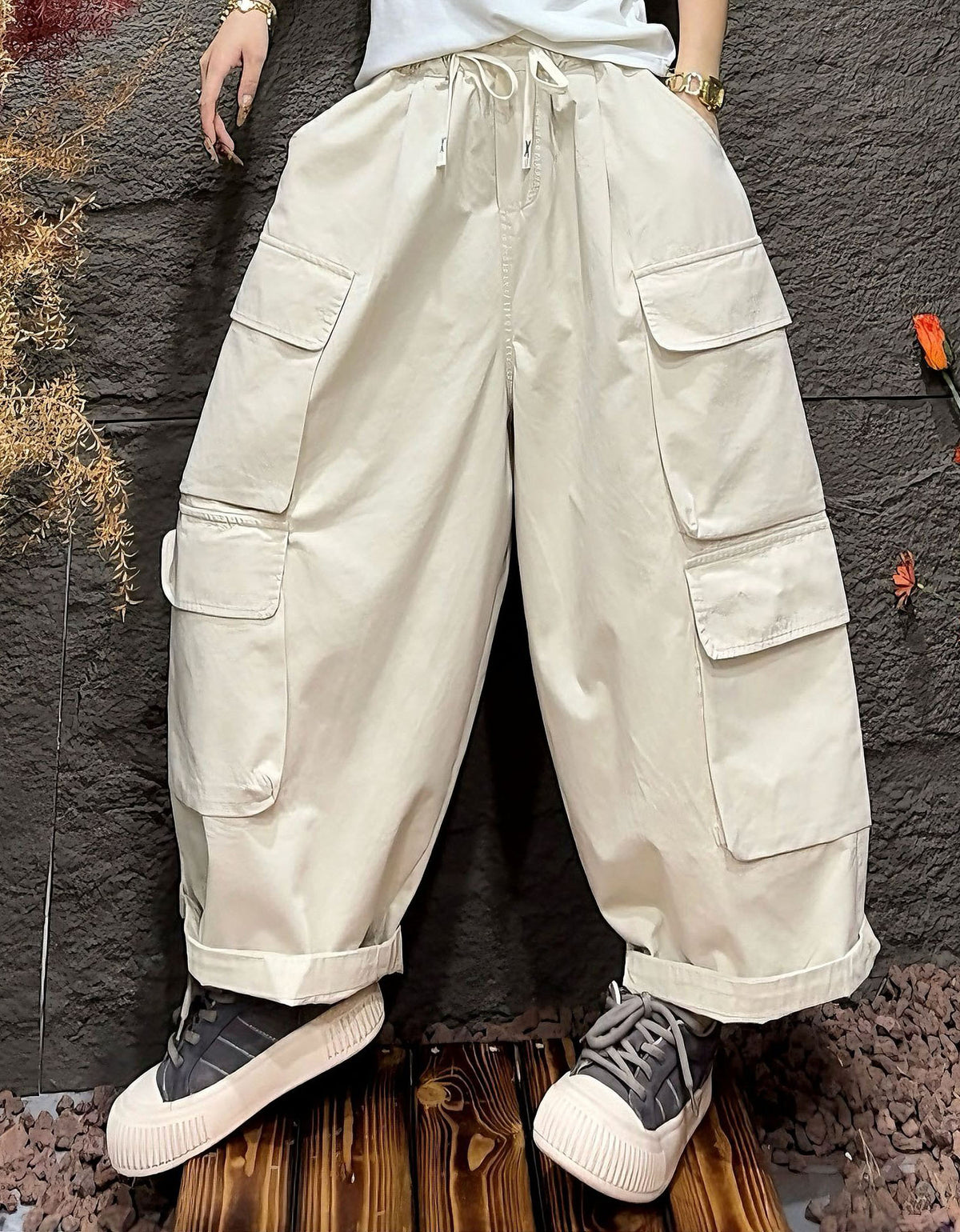 Beige cargo pants worn by a person against a dark textured wall.
