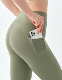 Person wearing green leggings with a pocket holding a phone on a white background