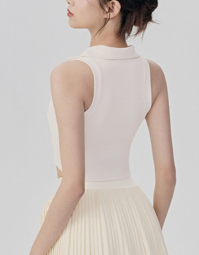 Woman wearing a light pink sleeveless top and beige pleated skirt on a plain background back view