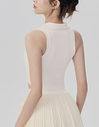 Woman wearing a light pink sleeveless top and beige pleated skirt on a plain background back view