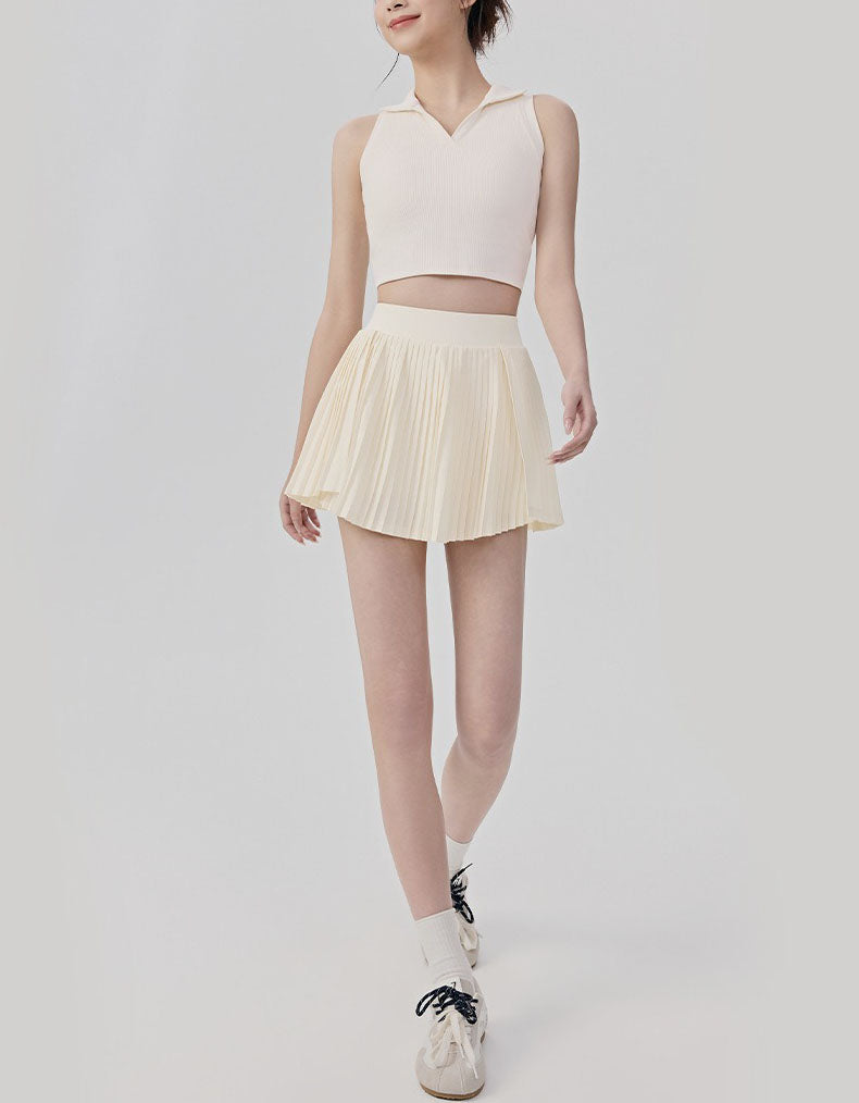 Person wearing a light pink sleeveless top and pleated skirt on a white background full view