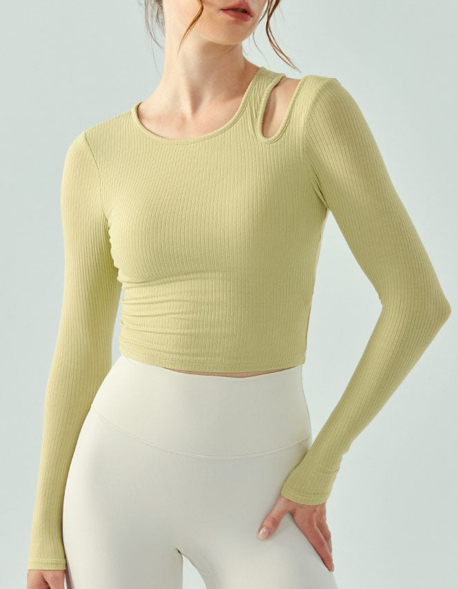 Person wearing a light green long-sleeve top and white pants on a plain background