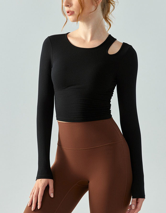 Person wearing a black long-sleeve crop top and brown leggings on a light gray background