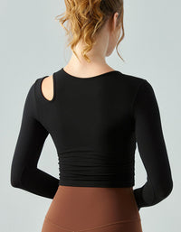 Person wearing a black long-sleeve top and brown pants on a light gray background back view