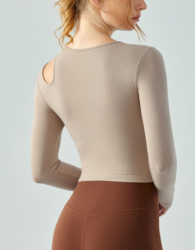 Person wearing a beige long-sleeve top and brown leggings on a light gray background back view