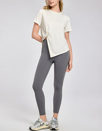 Person wearing a white t-shirt and gray leggings on a plain background