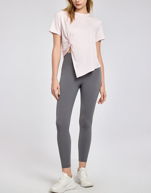 Person wearing a light pink t-shirt and gray leggings on a white background